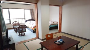 A hotel room with a bed, a dining table with a tray of snacks, a chair, and a television.