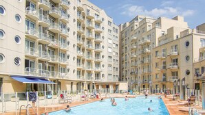 Une piscine entourée d’immeubles résidentiels à plusieurs étages, dotés de balcons.