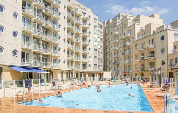 Ein Schwimmbecken, umgeben von mehrstöckigen Wohnhäusern mit Balkonen.