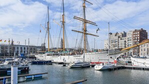 Un port de plaisance où sont amarrés de nombreux bateaux, dont un grand voilier.