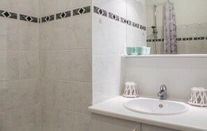 Ein Badezimmer mit einem weißen Waschbecken, einem Spiegel und einer Dusche.