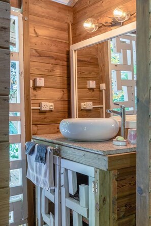 A wooden cabin bathroom with a white sink, a mirror, and a towel hanging on a rack.