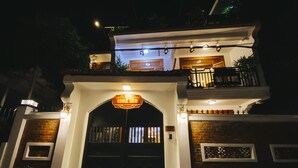 Een hotelentree met een bord waarop '1962 Inn' staat, met een traditionele boog, een balkon met leuningen en een bakstenen gevel.
