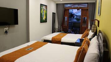 A hotel room with two beds, a flat-screen TV mounted on the wall, a painting, and a view of the outside through a door.