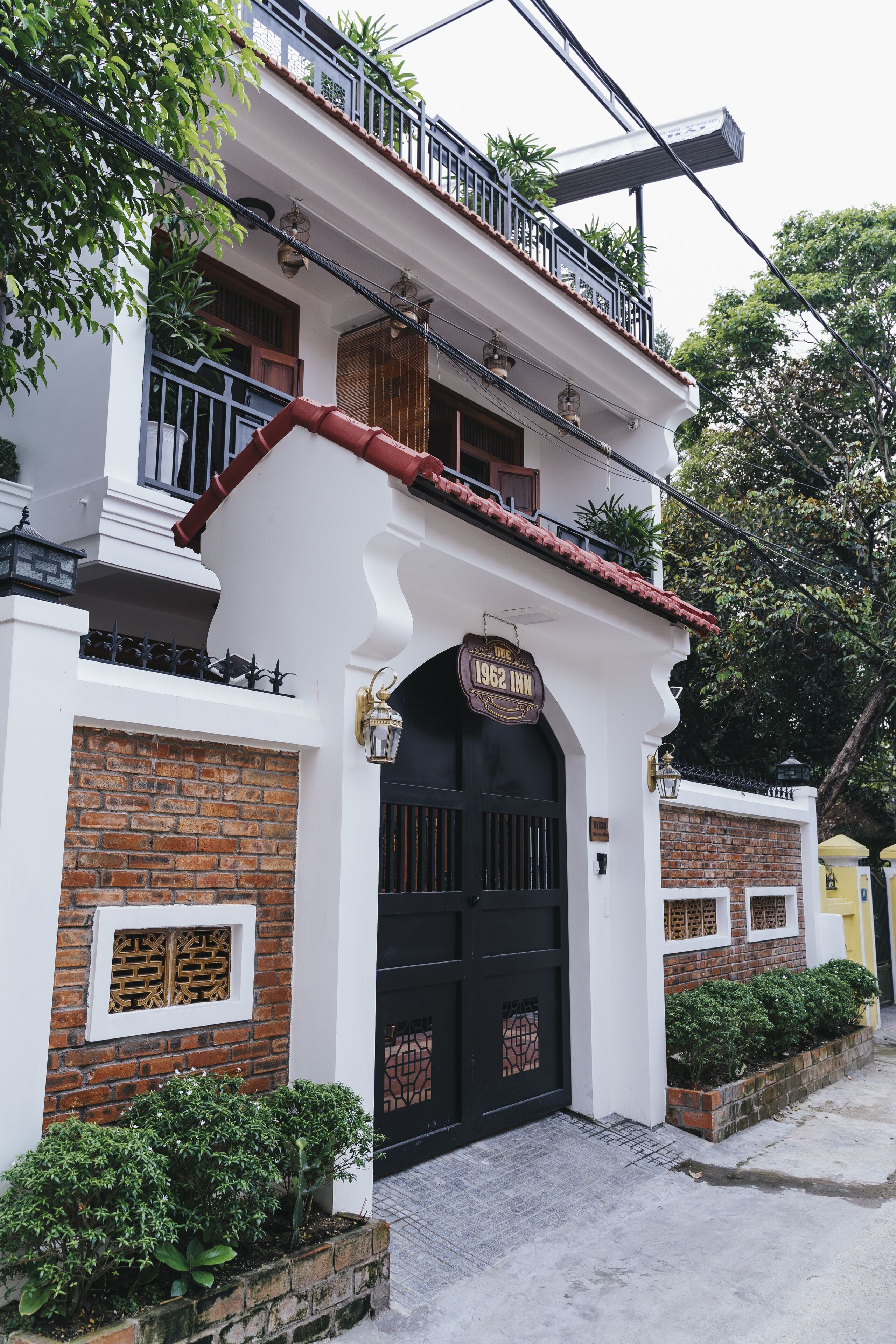 Un bâtiment à deux étages, doté d’un portail noir, d’un balcon et d’une enseigne indiquant « 1962 Inn ».