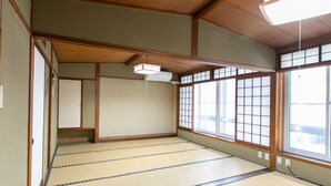 A traditional Japanese room with tatami flooring, sliding doors, and a ceiling fan. - Tabist Matsuekan (Matsue)