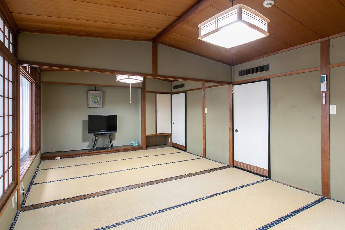 A traditional Japanese room with tatami flooring, sliding doors, and a television.
