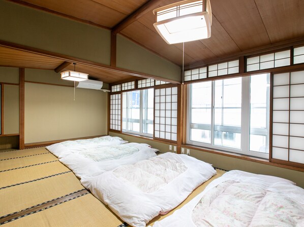 Una habitación japonesa tradicional con suelo de tatami, puertas correderas shoji y techo bajo.