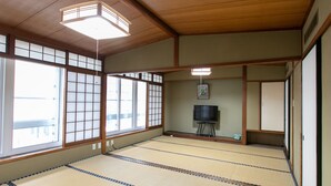 A traditional Japanese room with tatami flooring, sliding doors, and a television on a stand. - Tabist Matsuekan (Matsue)