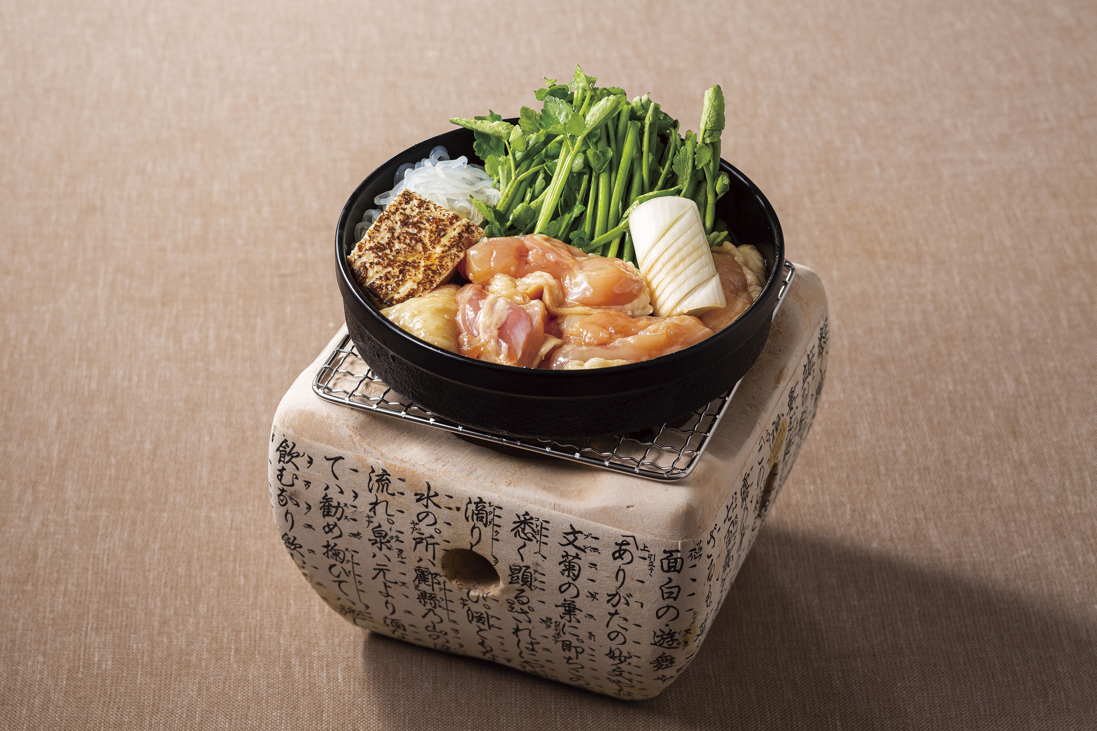 A bowl of food with various ingredients on a woven mat.