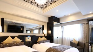 A hotel room with two beds, a large mirror, a TV, and a chair by the window.