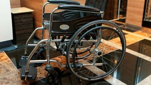 A wheelchair in a modern lobby with a marble floor and wooden paneling.