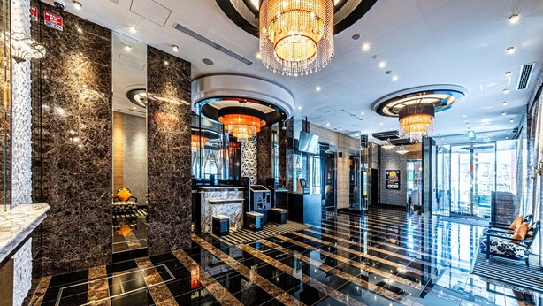 A modern lobby with a marble floor, a reception desk, and a chandelier.