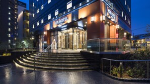 A multi-story hotel with a prominent entrance, outdoor steps, and a glass facade.