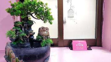 A potted bonsai tree with a small waterfall and an owl statue.