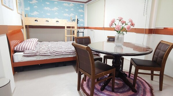 A bunk bed with a striped bedspread, a round dining table with four chairs, and a vase with pink flowers. - Healinghouse Peakjang (Buyeo)