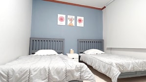 A bedroom with two single beds, a nightstand with a lamp, and three framed floral artworks on the wall. - Healinghouse Peakjang (Buyeo)