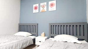 A bedroom with two beds, a nightstand, and three framed pictures on the wall. - Healinghouse Peakjang (Buyeo)