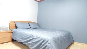 A bedroom with a bed, a nightstand, and a wall lamp.