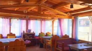 A cozy room with wooden furniture, a table, and chairs. - Happy Times Theme Inn (Deqin)