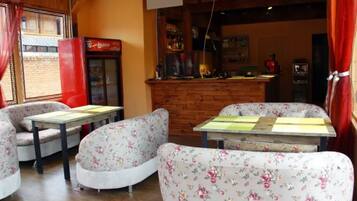 Una habitación acogedora con sofás de estampado floral y una mesa de madera, un refrigerador rojo y una zona de bar con mostrador.