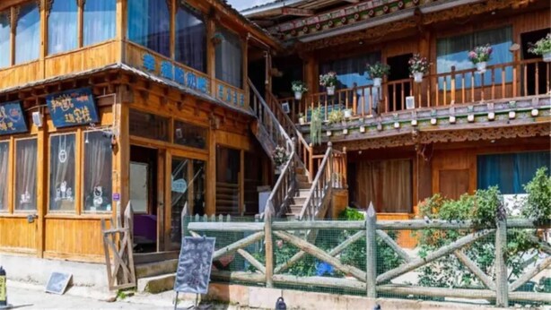 A traditional wooden building with multiple balconies and a staircase leading to the upper levels. - Happy Times Theme Inn (Deqin)