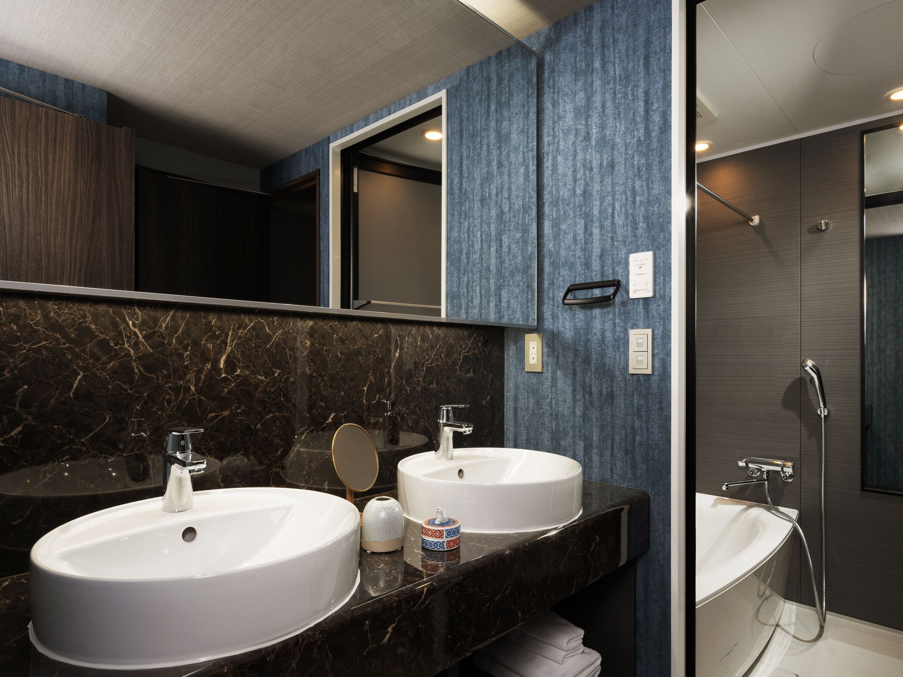 A modern bathroom with two sinks, a large mirror, and a shower area.