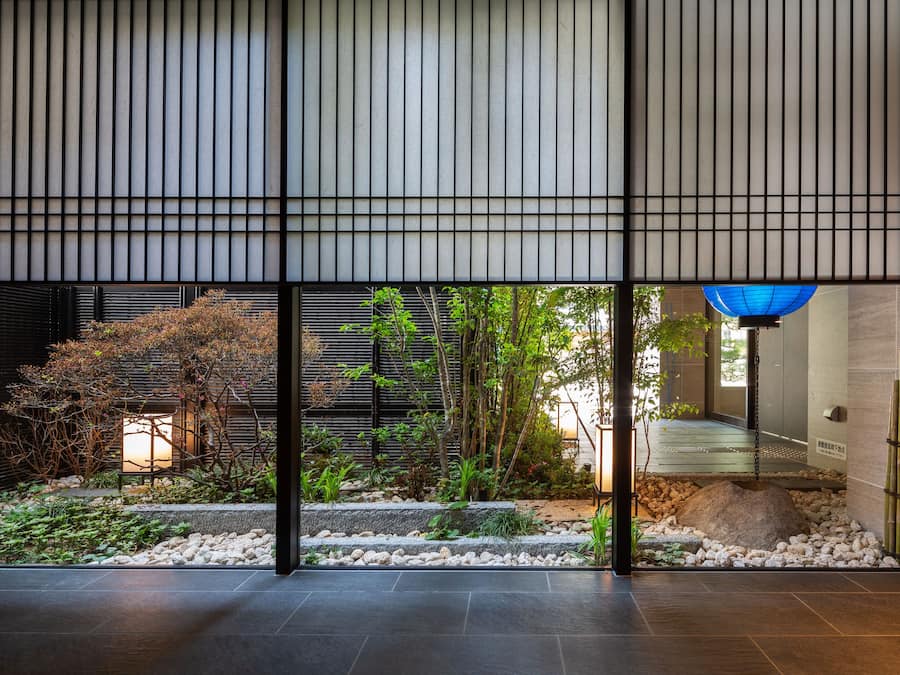 A modern interior with a view of a garden through a glass partition.