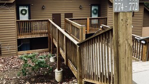 A wooden cabin with a balcony and a staircase leading to the entrance. - Newly Updated Cozy Condo in the Heart of Wintergreen!  Pet friendly. (Wintergreen)