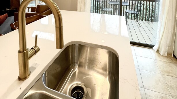 A modern kitchen with a stainless steel sink, a pendant light, and a view of a wooden deck through large windows. - Newly Updated Cozy Condo in the Heart of Wintergreen!  Pet friendly. (Wintergreen)