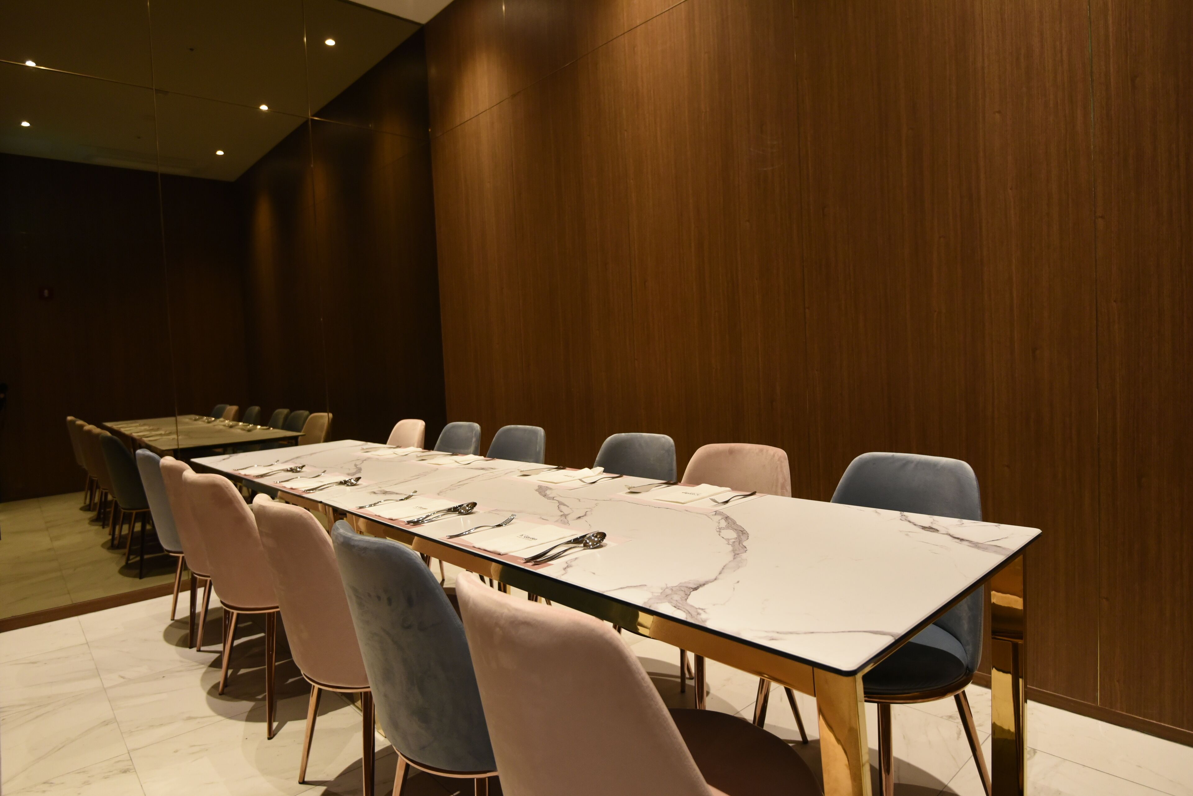 A conference room with a long table and chairs, wooden walls, and a marble table surface.