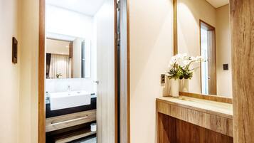 A modern bathroom with a wooden vanity, a large mirror, and a white sink.