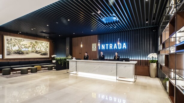 A modern reception area with a marble counter, a large framed artwork, and a sign that reads "INTRADA". - Hotel Intrada Icheon (Icheon)