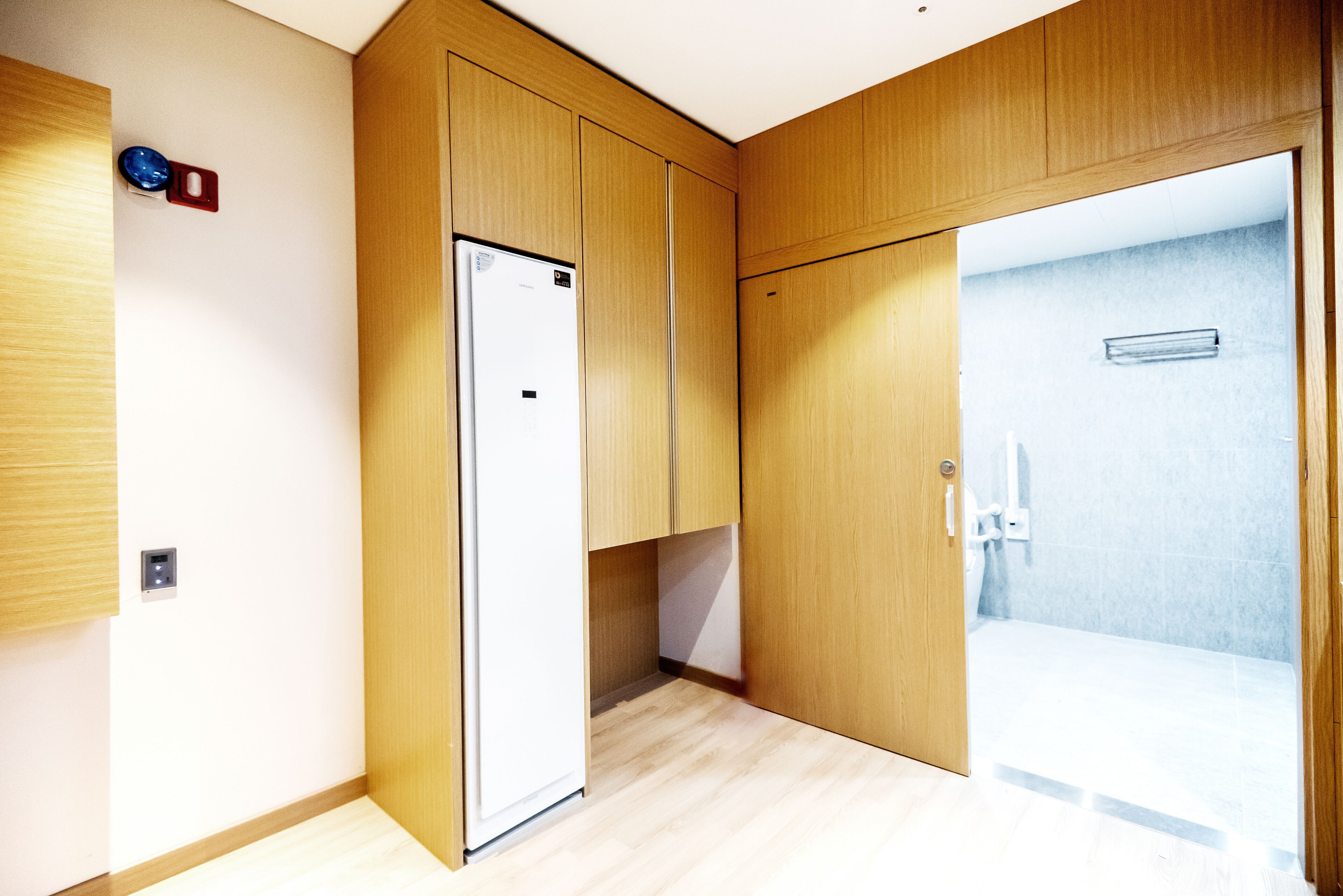 A modern bathroom with wooden cabinetry, a shower area, and a visible toilet.