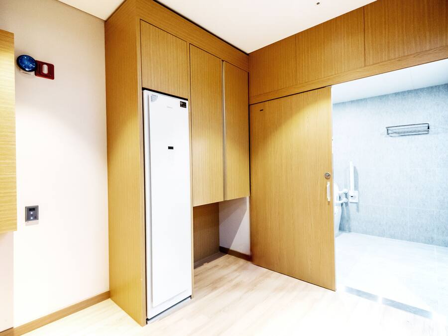 A modern bathroom with wooden cabinetry, a shower area, and a visible toilet.