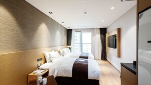 A modern hotel room with two beds, a flat-screen TV, a bedside table with a lamp, and a large window with curtains. - Hotel Intrada Icheon (Icheon)