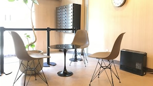 Una habitación con una mesa redonda, cuatro sillas, un reloj en la pared y una planta.