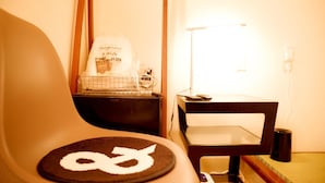 Una habitación con una silla de diseño circular, una mesita con una lámpara y un estante en la pared con un bolso y una cesta.