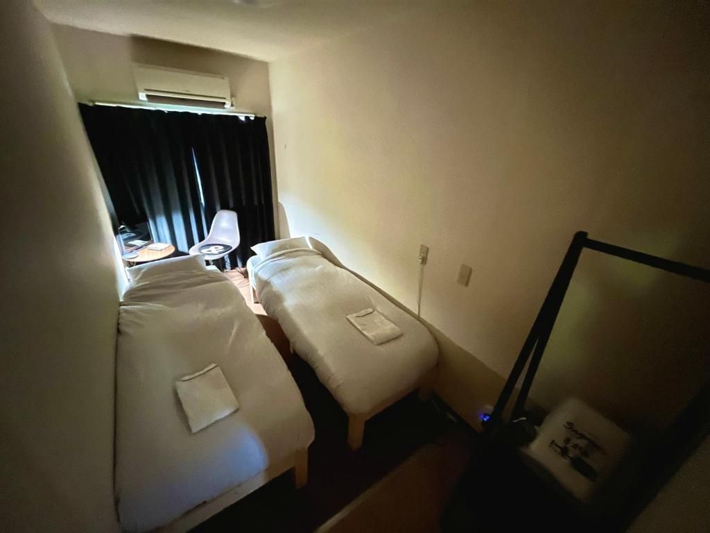 A hotel room with two beds, a desk, a chair, and a mirror.