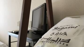 A hotel room with a bed, a desk with a computer, and a bag of toiletries.