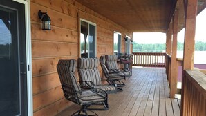 A covered porch with wooden flooring and striped chairs. - Peaceful Meadows (Custer)