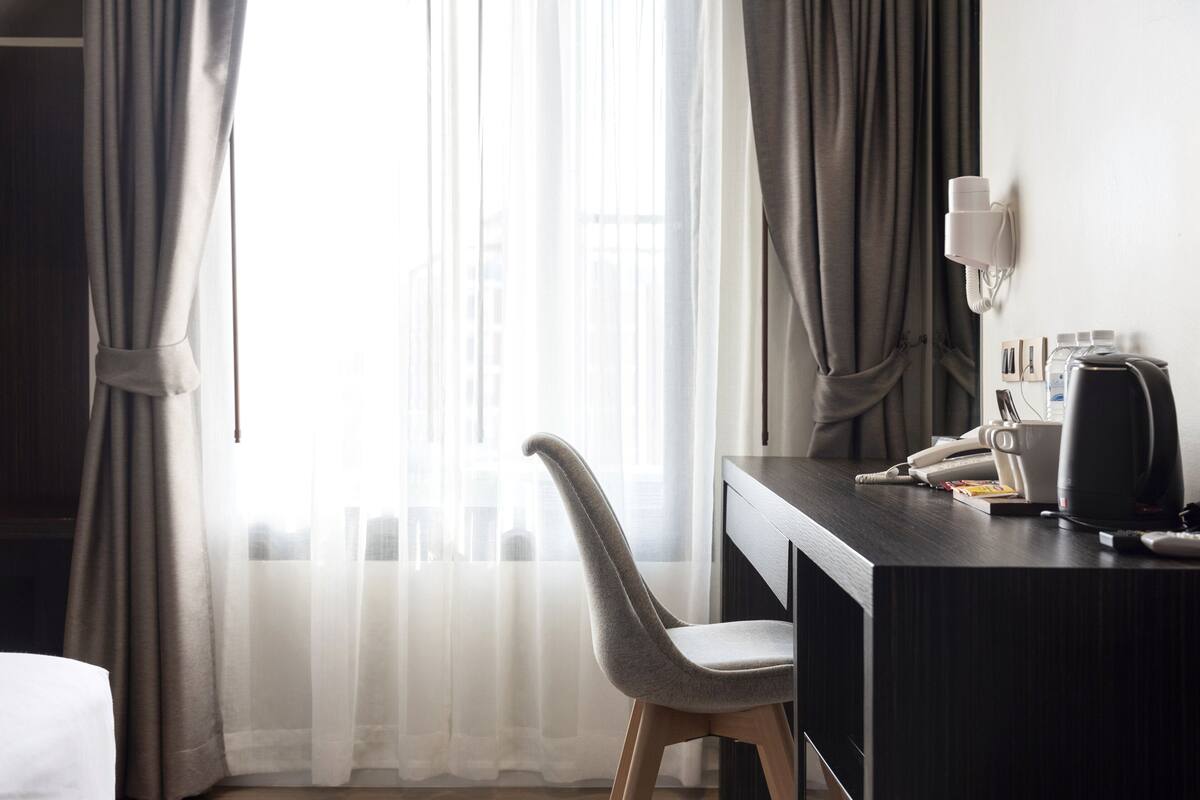 A hotel room with a desk, chair, and a telephone.