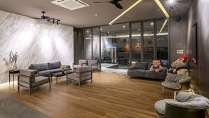 A modern living room with a sofa, chairs, a coffee table, and a fireplace. There are two teddy bears on the sofa. - Xotel (Khon Kaen)