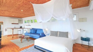 Une chambre à coucher avec un lit à baldaquin, un canapé bleu et, au fond, une petite cuisine.