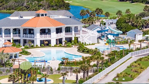 A large resort with multiple swimming pools, a golf course, and a lighthouse in the background.