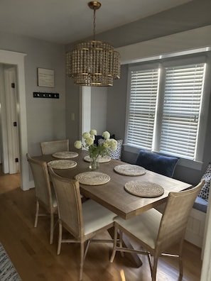 Een eetruimte met een houten tafel, geweven placemats en rieten stoelen.