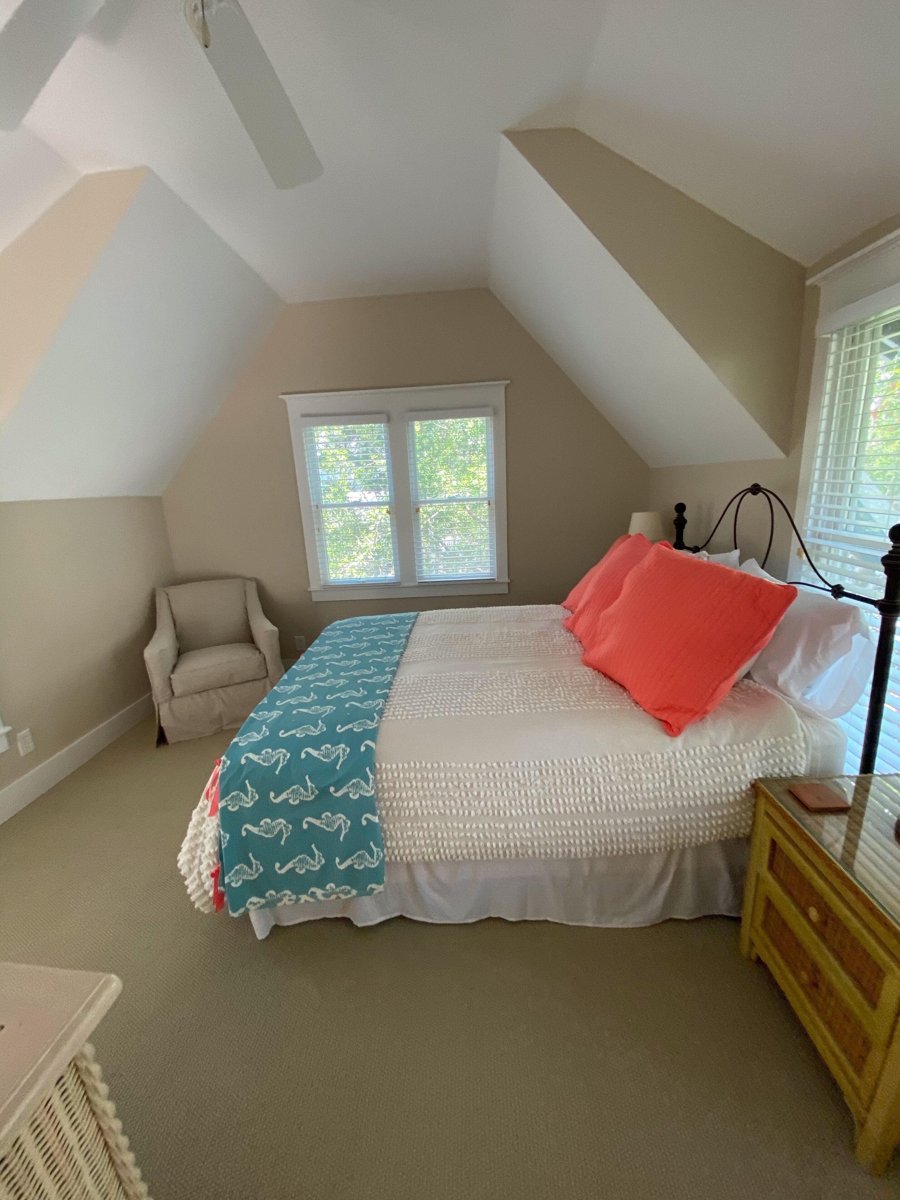 Une chambre à coucher avec un lit, une chaise, une table de chevet et une fenêtre.