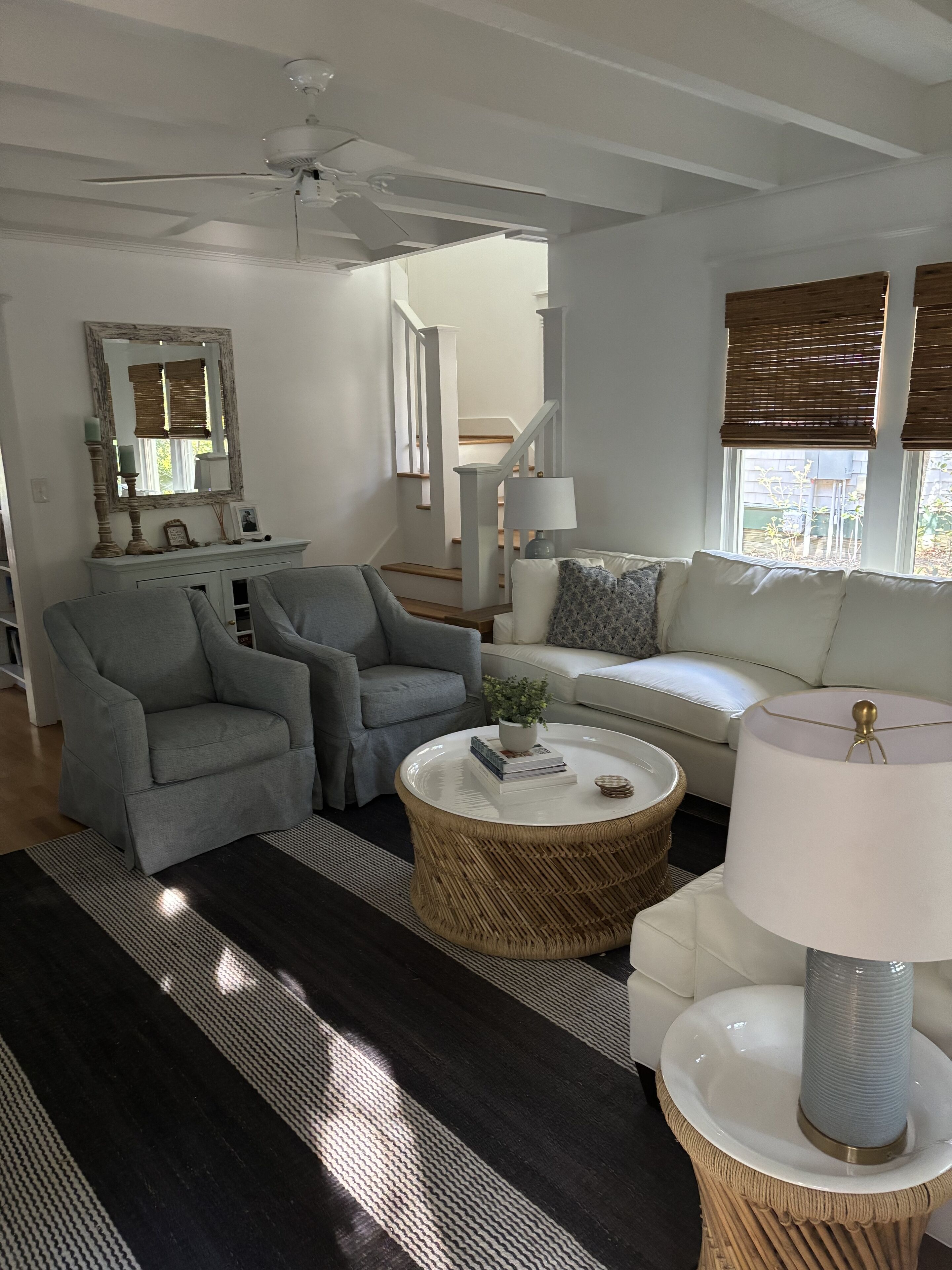 Un salon moderne avec un canapé gris, deux fauteuils, une table basse et une lampe.