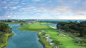 A golf course with a river running through it, surrounded by greenery and residential buildings.