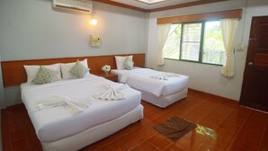 Habitación de hotel con dos camas, cabecero de madera, ventana con cortinas y una puerta.